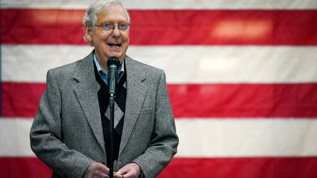 Mitch McConnell laughing in front of an American flag.