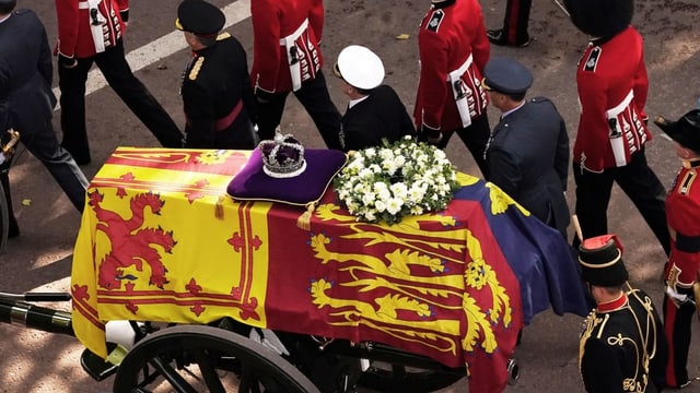 Der Sarg der Queen wird von einem Kanonenwagen gezogen, geschmückt mit einem Tuch, weissen Blumenkranz und der Krone.