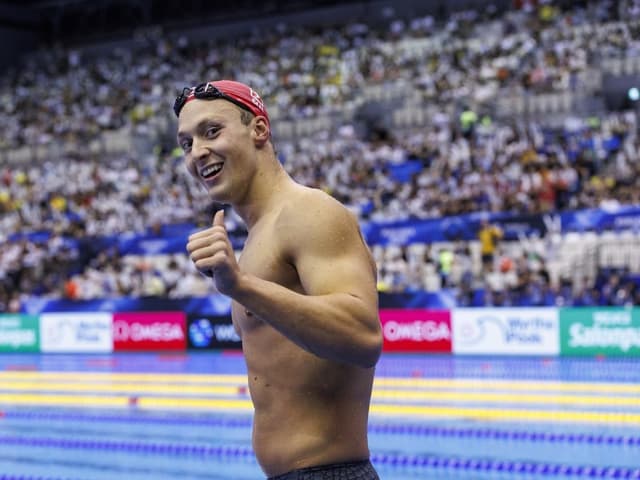 Schwimmer nach dem Wettkampf, Daumen hoch, in Schwimmhalle.