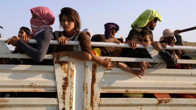 Jesidische Frauen und Männer auf der Ladefläche eines Lastwagens auf der Flucht.