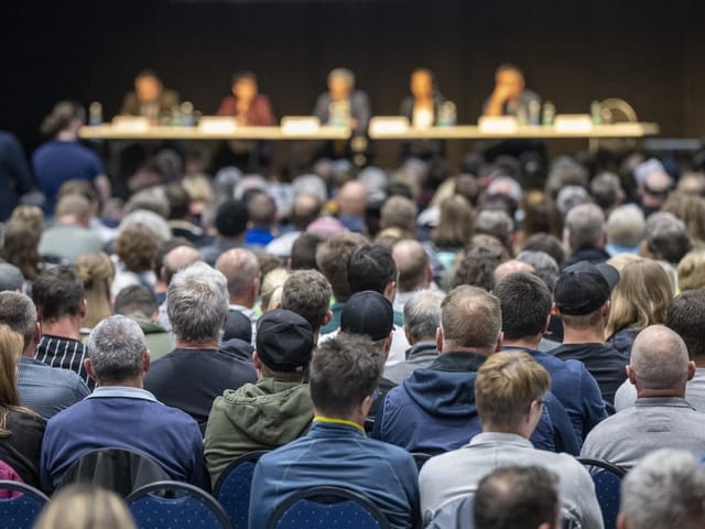 Publikum hört einem Podiumsgespräch mit mehreren Rednern bei einer Veranstaltung zu.