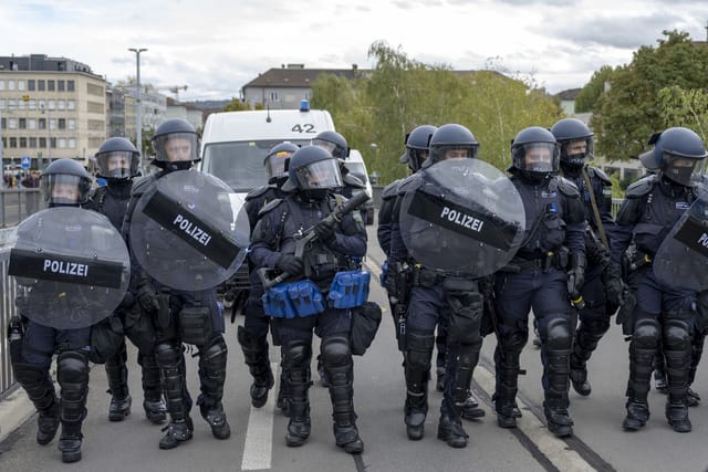 Viele Polizisten stehen auf einer Brücke mit Schildern.