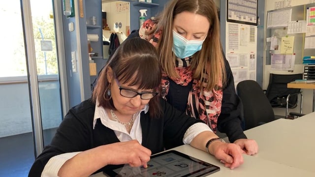 Zwei Frauen schauen auf ein Tablet.