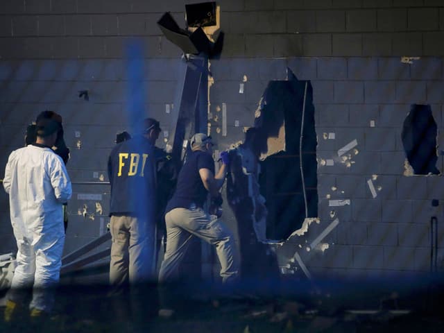 Forensiker bei der Arbeit an einer Aussenwand des Gebäudes.