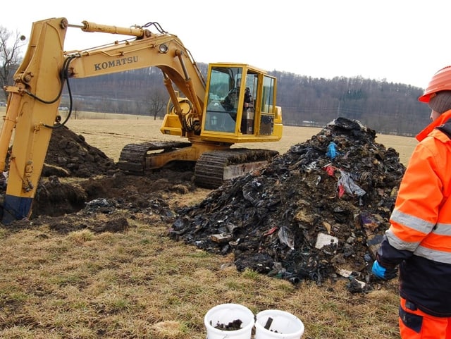 Bagger fördert abfalldurchsetztes Erdreich ans Tageslicht