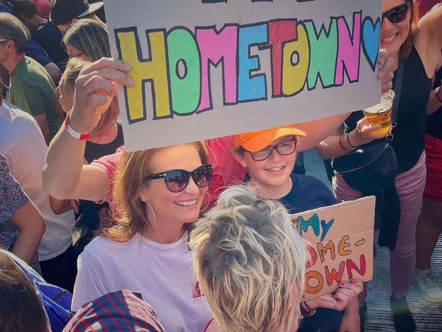 Judith Wernli am Bruce Springsteen Konzert mit Bruce Springsteen Fans, die ein «My Hometown» Plakat hochhalten