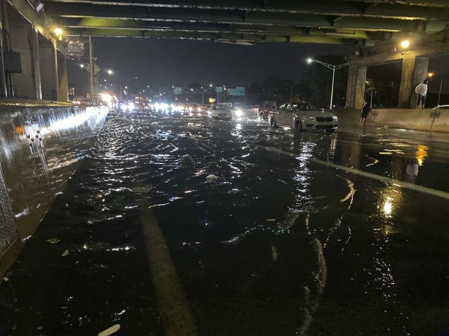 Menschen stehen unter einer Unterführung, während ihre Autos auf dem Long Island Expressway liegen bleiben.