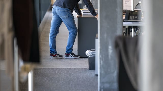 Person im Büro steht an einem Schreibtisch.