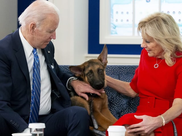 Die Bidens sitzen auf einem Sofa und streicheln Commander, der zwischen den beiden sitzt.