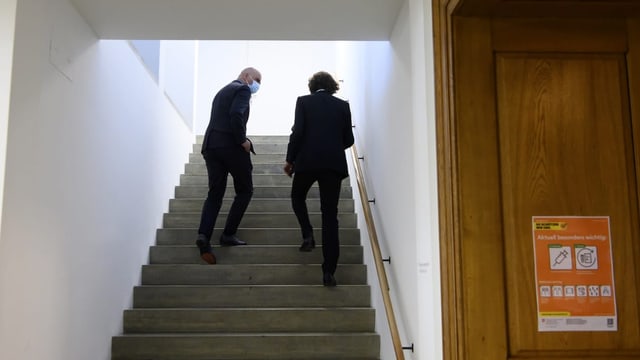 Ein Bild von hinten von Alain Berset (links) und Peter Lauener (rechts)