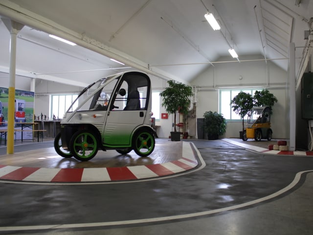 Eine kleine Teststrecke mit einem Elektromobil in einer Montagehalle.