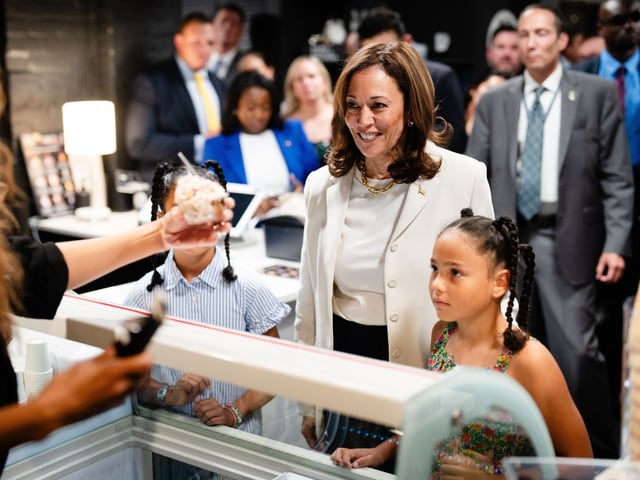 Kamala Harris inmitten von Menschen, lächelndes Kind vor Vitrine