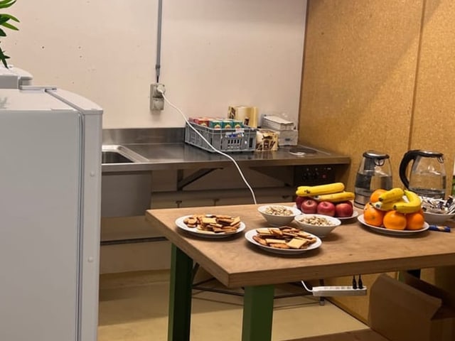 Kühlschrank, Waschbecken und Tisch mit Snacks