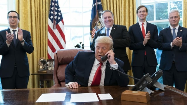 Trump on the phone.  Behind him are men clapping.