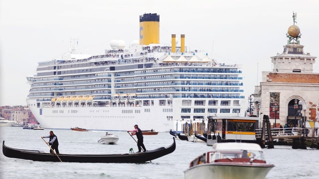 Eine Gondel vor eine Kreuzfahrtschiff in Venedig.