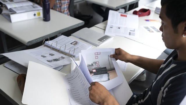 Ein junger Mann schaut sich Übungen in der Schule an.