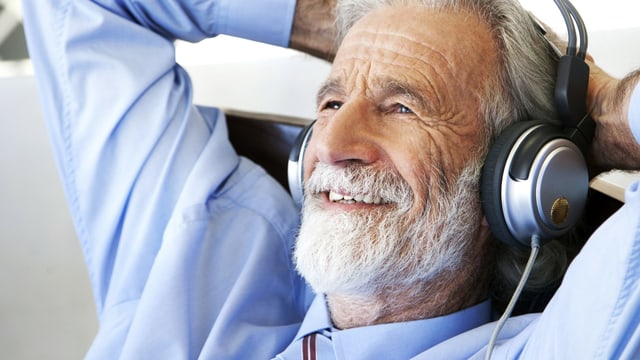 Vitaler Senior hört mit zufriedenem Gesichtsausdruck Musik.