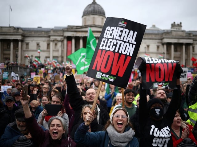 Menschen demonstrieren in London mit Plakaten.