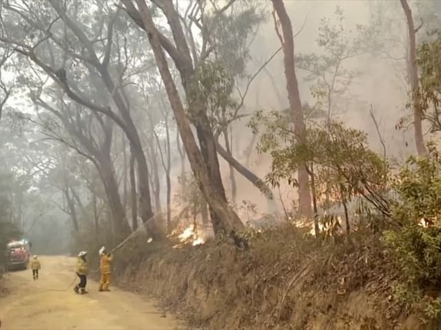 Feuerwehrleute bei den Löscharbeiten mit einem Schlauch.