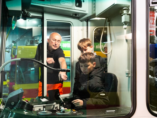 Ein Schüler sitzt im Führerstand und kriegt Anweisungen von einem Mitarbeiter des Verkehrsunternehmens.