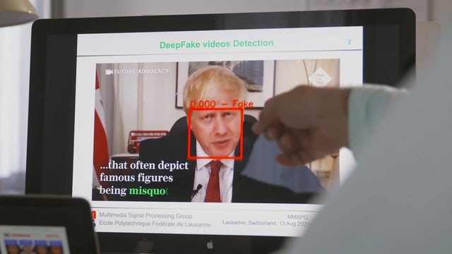 Mann zeigt am Bildschirm auf ein Deep-Fake-Video von Boris Johnson.