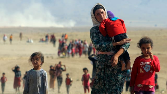 Frauen und Kinder marschieren durch die irakische Wüste.