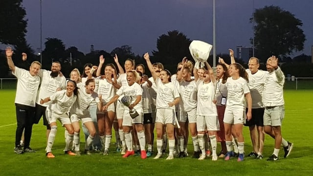 Jubelnde Fussballerinnen in weissen Dresses und Hosen.