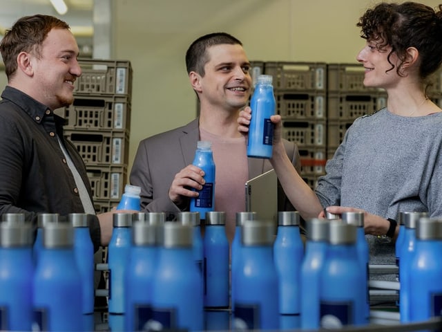 Menschen bei der Inspektion von blauen Wasserflaschen in einer Fabrik.