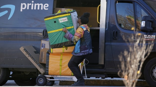 Amazon-Lieferantin hebt ein Paket in einen Bus.