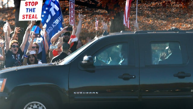 Trump in the car passes the trailers.