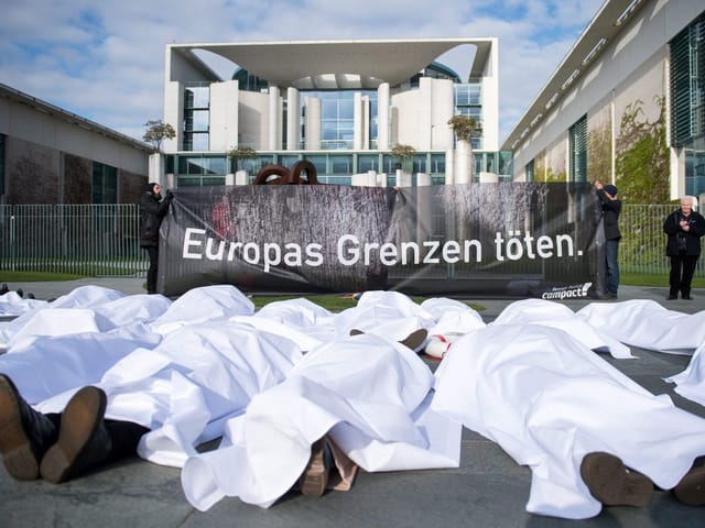 Demonstranten liegen vor dem Bundeskanzleramt mit einem Transparent «Europas Grenzen töten» auf dem Boden.