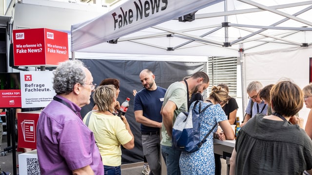 Michael Rauchenstein steht am Fake-News-Stand und unterhält sich mit Interessierten.