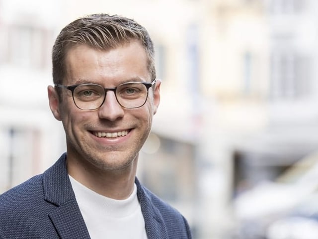 Ein Mann mit Brille, weissem Shirt und Sakko.