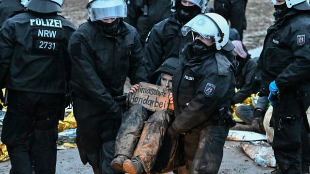 Polizisten tragen Demonstranten weg