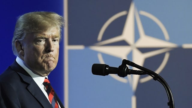 Trump vor Mikrofon vor Nato-Logo.