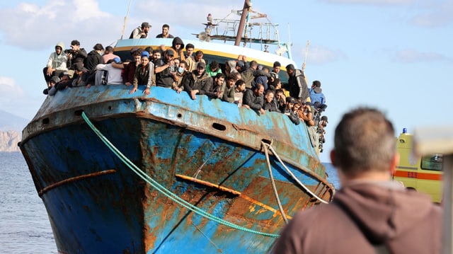 Die Menschen stehen auf einem rostigen, blauen Schiff.