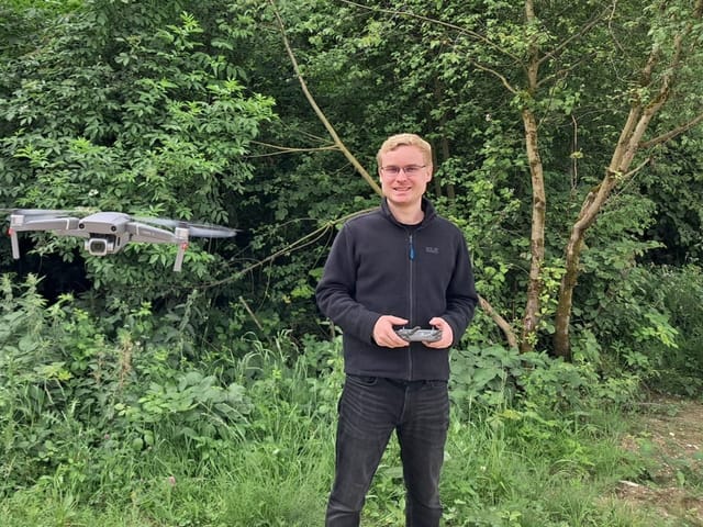 Mann steuert Drohne im Wald.