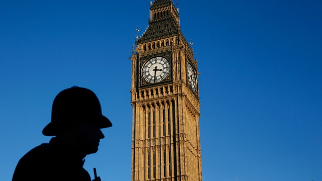 Big Ben vor blauem Himmel, im Vordergrund sind die Umrisse eines britischen Polizisten erkennbar