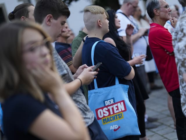 Menschenmenge mit AfD-Tasche mit der Aufschrift 'Der Osten macht's!'