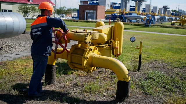 Ein Arbeiter dreht an einem Rad einer Gasleitung