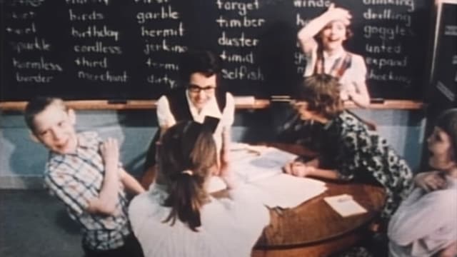 Kinder und Lehrerin sitzen um Tisch