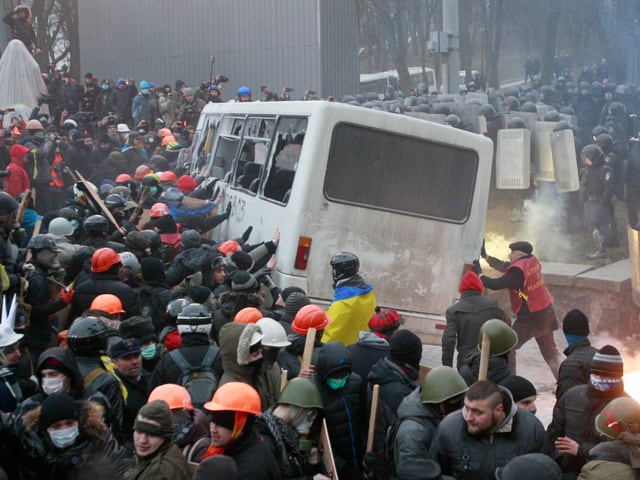 Demonstranten greifen Polizeibus an.