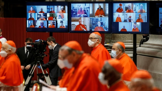 Cardinals, in the background a videowall with images of other cardinals.