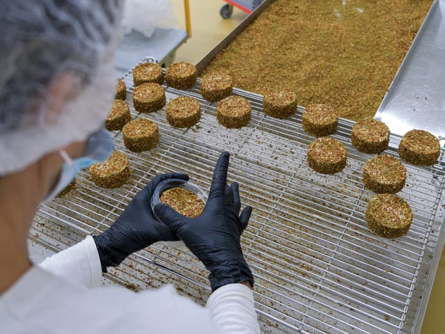 Mitarbeiter formt pflanzliche Burger-Patties in einer Fabrik.