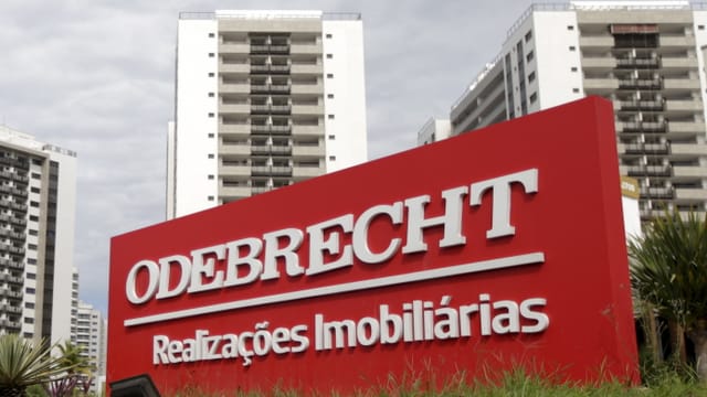 Logo des Konzerns Odebrecht vor einer Hochhaussiedlung.