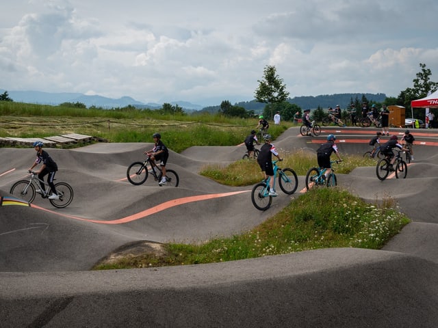 Jugendliche auf Velos fahren auf einem hügeligen Trail.