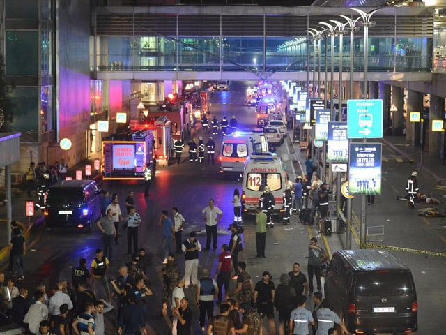 Menschenansammlung und Ambulanzautos vor Flughafen