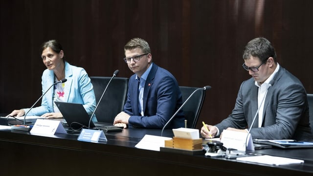 Drei SVP-Nationalräte sitzen an einem Tisch und geben eine Pressekonferenz.