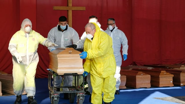 Various coffins and people with protective masks.