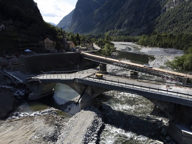 Neue Brücke im Bau über einen Fluss in einer bergigen Landschaft.